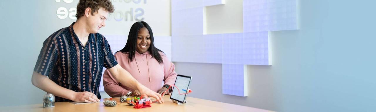 2 students standing at a table looking at an ipad